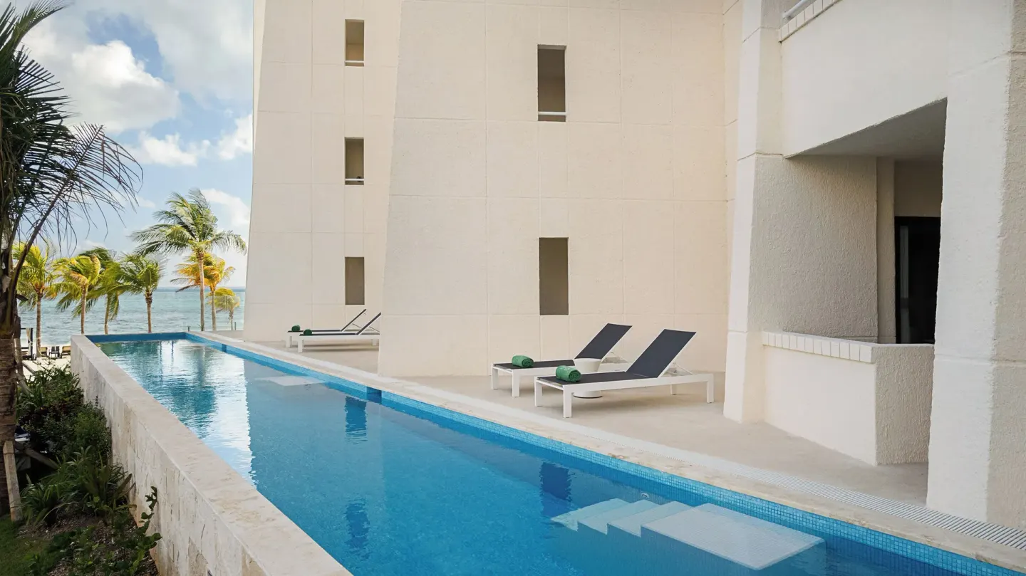 The Level Room Swim Up poolside terrace at Melia Casa Maya Cancun with loungers and ocean beyond.