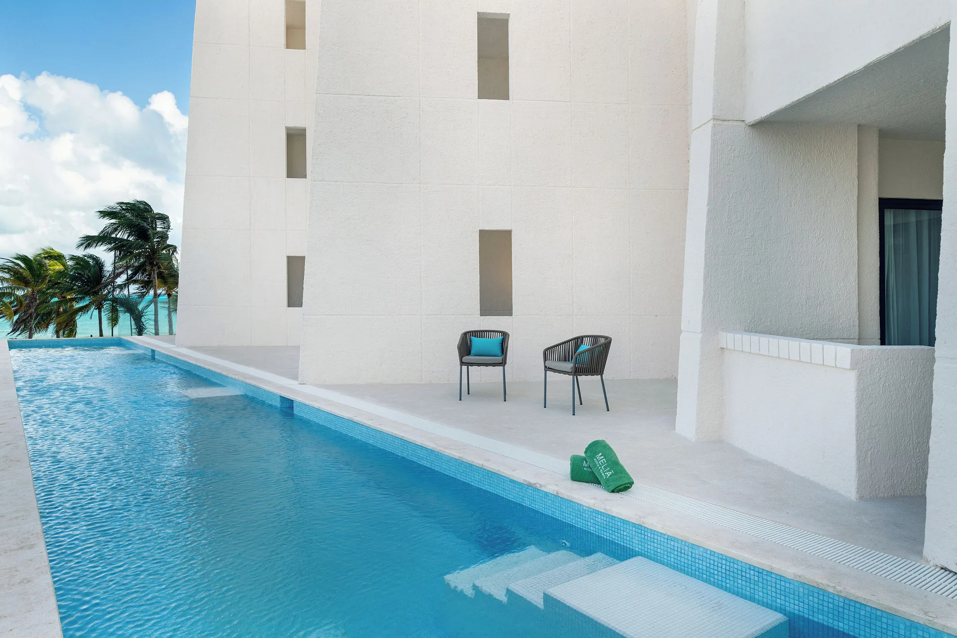 The Level Room Swim Up terrace and pool at Melia Casa Maya Cancun with two chairs by the water.