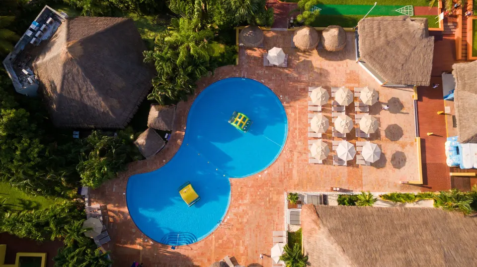 Aerial view of kidney-shaped pool with umbrellas and palapas at Melia Cozumel