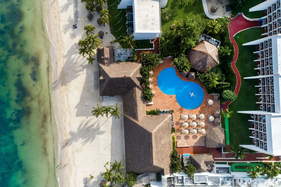 Aerial view of the resort pool, palapa roofs and the beach shoreline at Melia Cozumel
