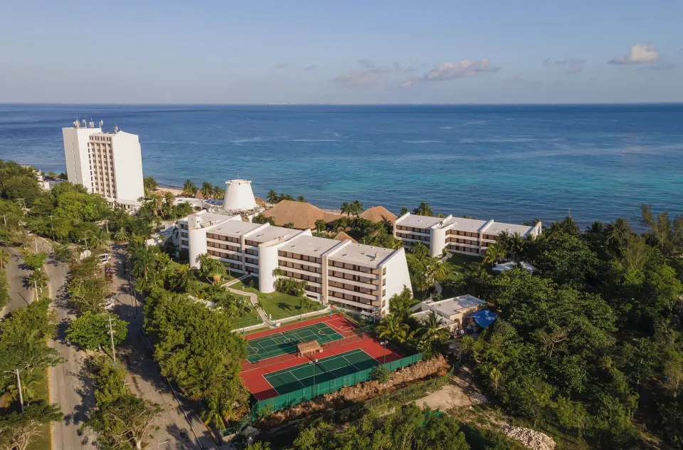 Resort aerial view showing tennis courts and low-rise buildings at Melia Cozumel