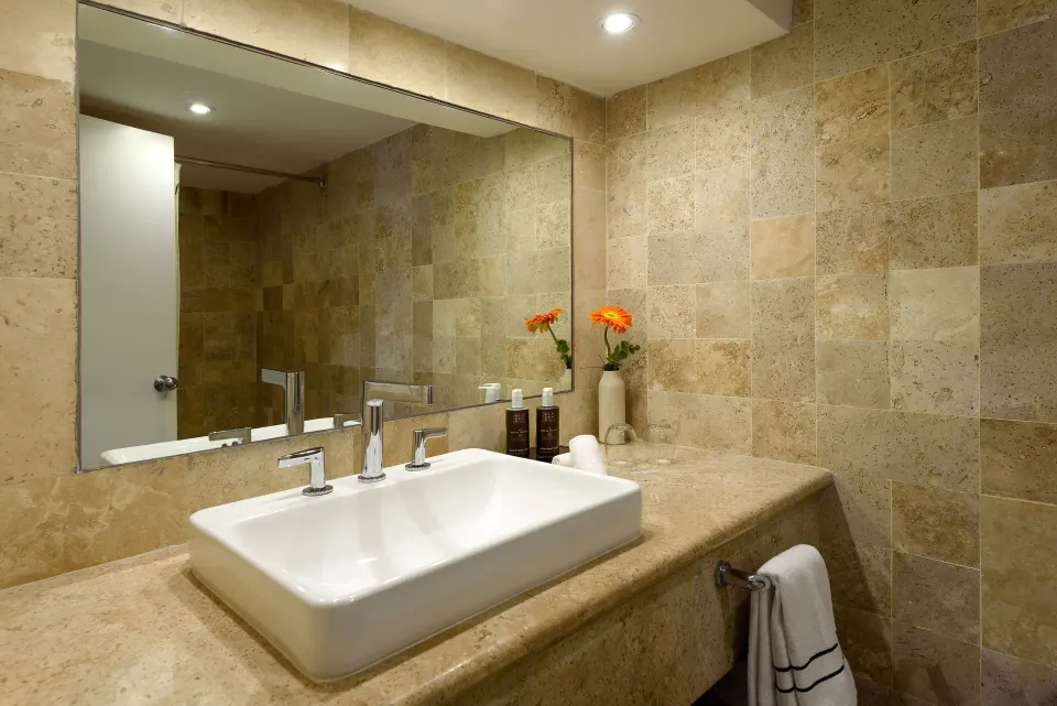 Square vessel sink and towel on a stone countertop in a tiled bathroom at Melia Cozumel