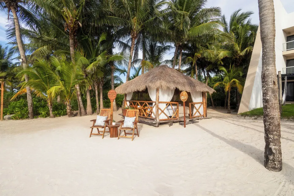 Thatched beach cabana on white sand among palm trees at Melia Cozumel
