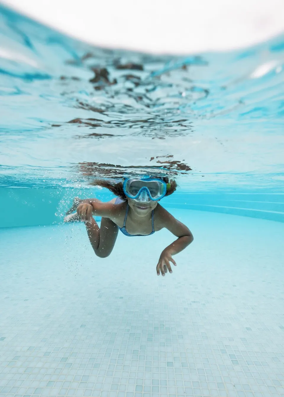 Child snorkeling underwater in a clear pool at Melia Cozumel