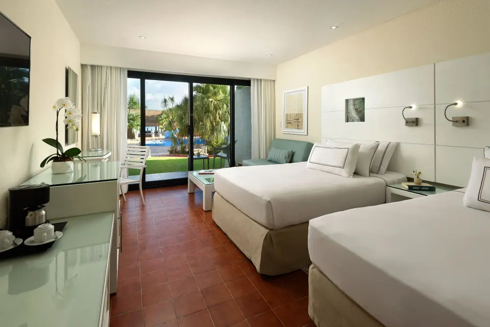 Garden-view guest room with two beds and sliding doors at Melia Cozumel.