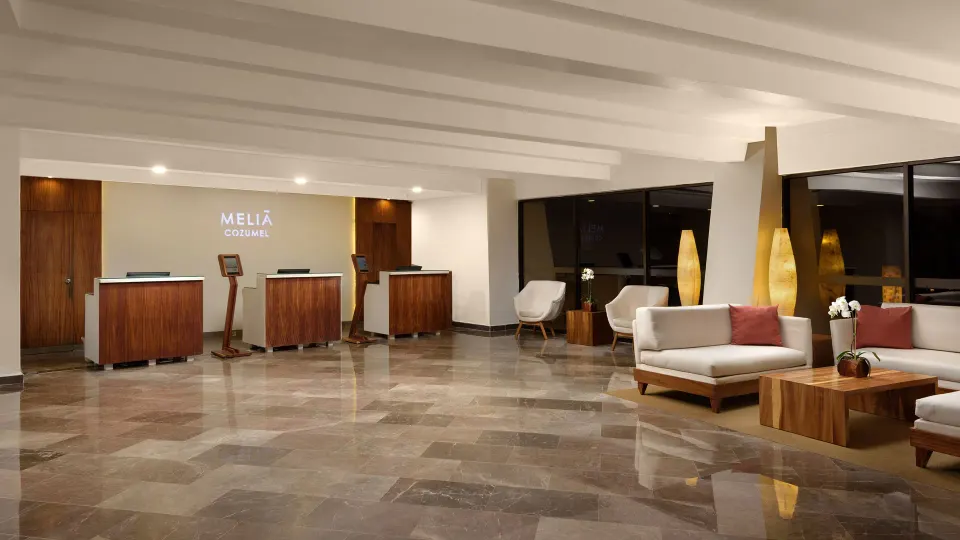 Melia Cozumel lobby with reception desks and seating by the windows.
