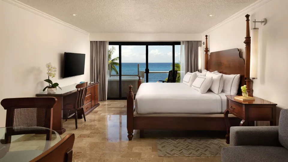 Suite sitting area at Melia Cozumel with chaise, chairs and sliding doors to an oceanfront patio.