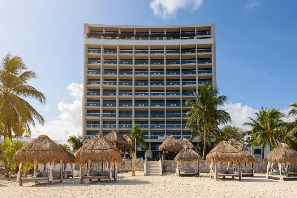 Front view of the resort tower and palapas on the beach at Melia Cozumel.