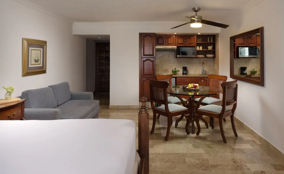 Suite interior at Melia Cozumel with a bed, sofa and small dining area with kitchenette.