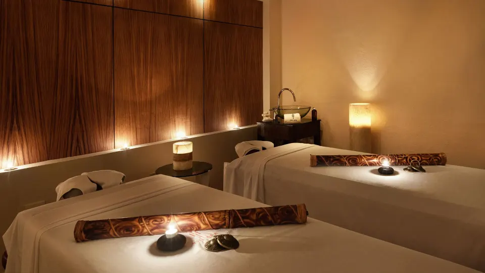 Dimly lit spa treatment room with two massage tables at Melia Cozumel