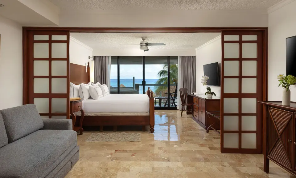 Spacious suite with sliding wooden room divider and ocean balcony at Melia Cozumel.