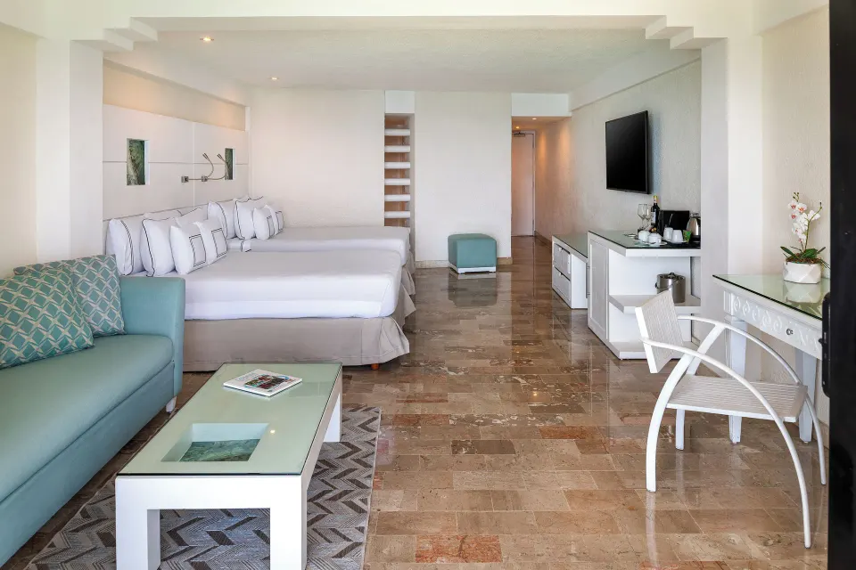 Spacious suite interior with two beds and seating area at Melia Cozumel.