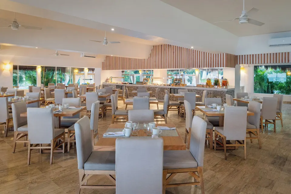 Spacious indoor buffet-style dining room with tables and neutral seating at Melia Cozumel