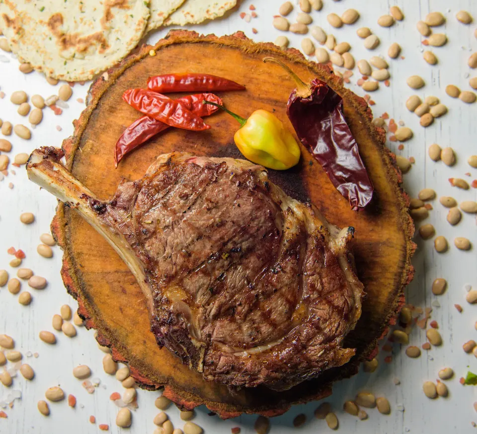Grilled rib-eye steak on a wooden board with chiles and beans at Melia Cozumel