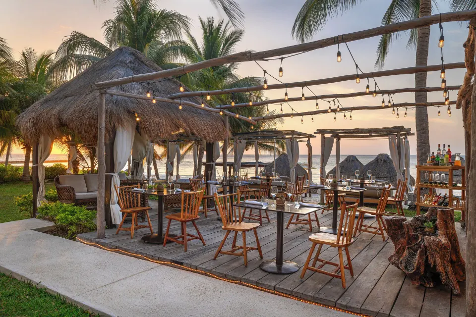 Outdoor wooden deck dining area with palapa shades and string lights at Melia Cozumel