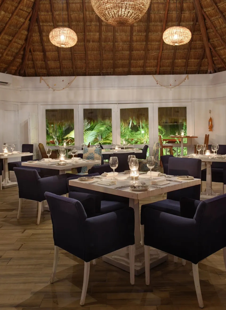 Indoor palapa-style dining area with navy chairs at Melia Cozumel