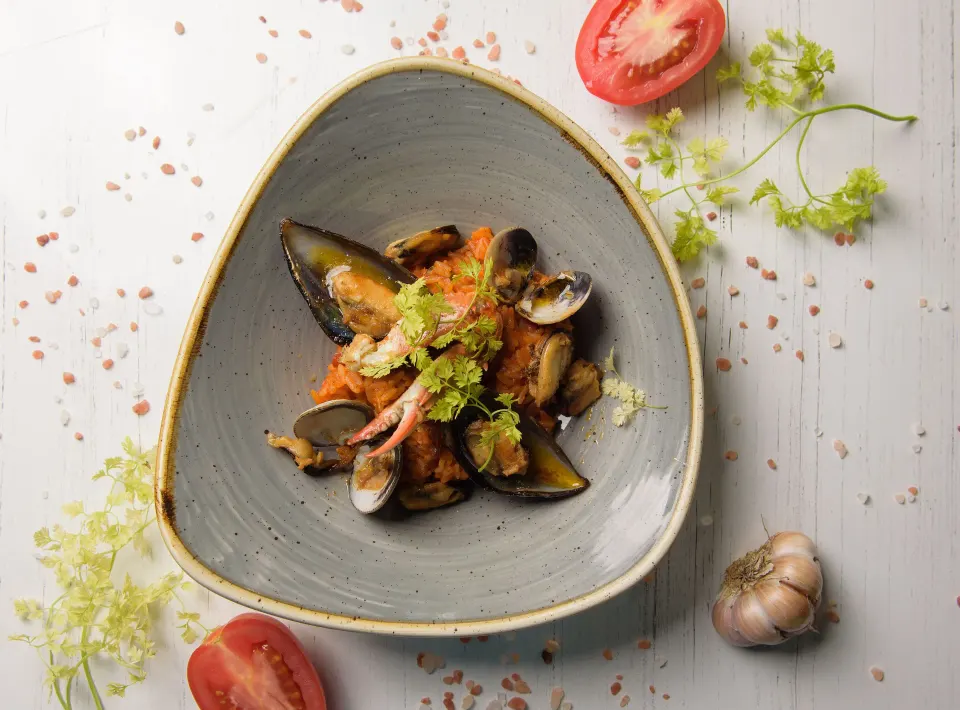 Bowl of mussels and clams with herbs on a table at Melia Cozumel