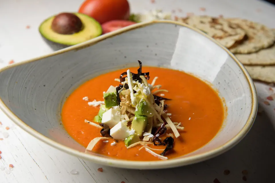 Tomato-based soup garnished with avocado, cheese and herbs at Melia Cozumel