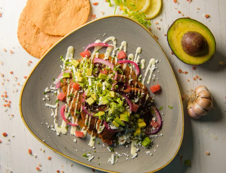 Tostadas topped with diced vegetables, cheese and drizzle at Melia Cozumel
