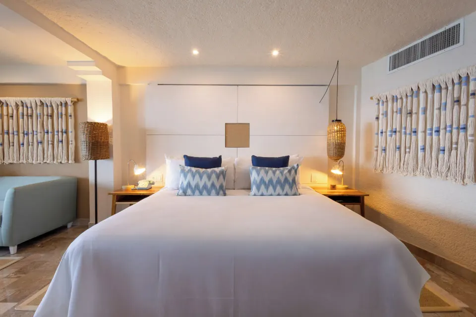 ZEL Room Ocean View centered king bed with decorative wall hangings at Melia Cozumel