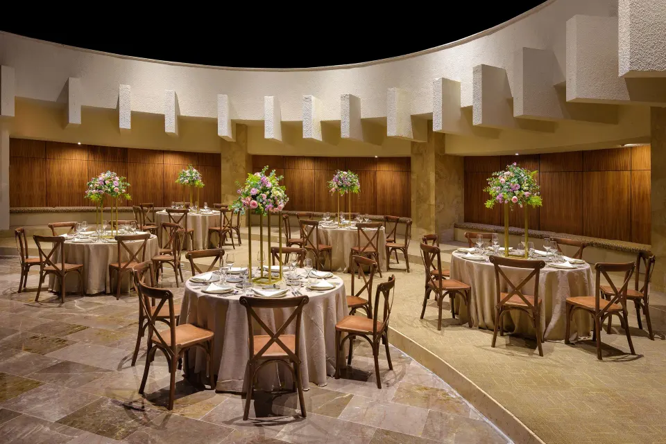 Round banquet tables set for an event in a curved room at Melia Cozumel