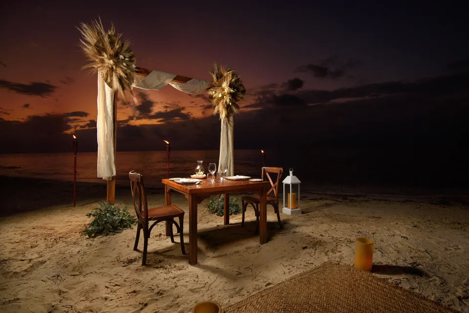 Romantic beachfront dining setup on the sand at Melia Cozumel at sunset