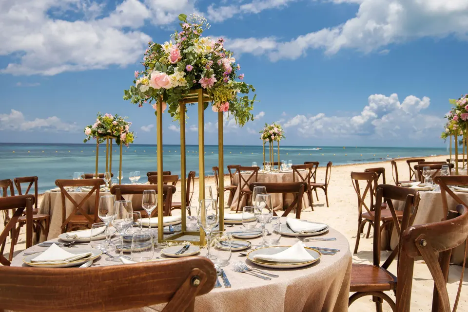 Round reception tables with floral centerpieces on the beach at Melia Cozumel