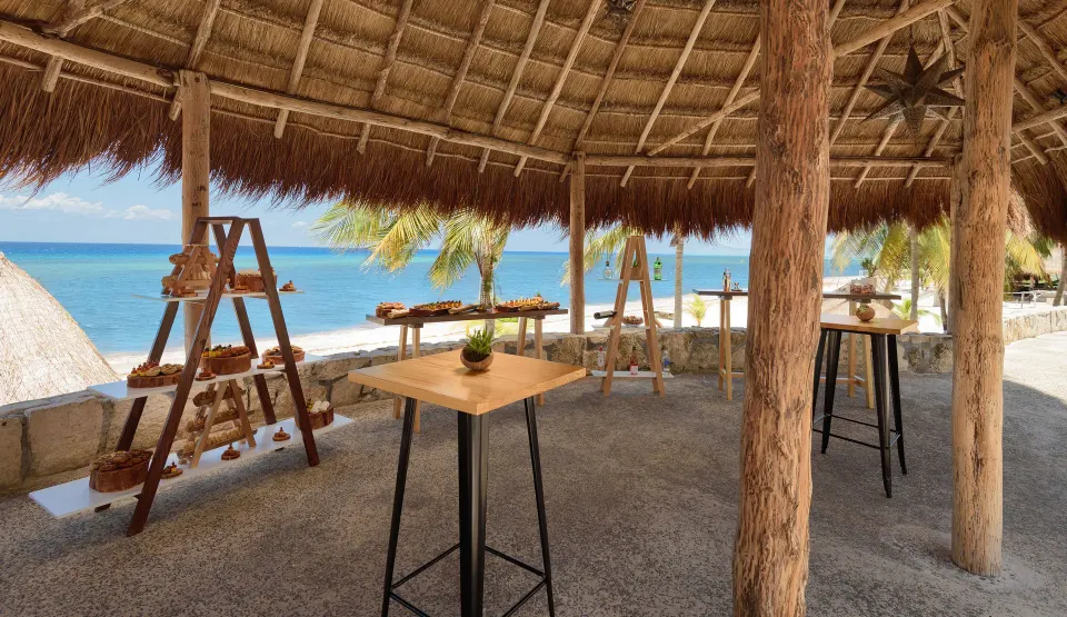 Thatched palapa with high tables and snack displays overlooking the sea at Melia Cozumel.