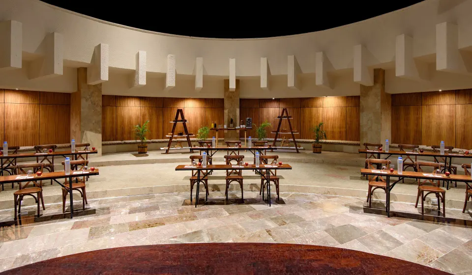 Wide view of an event room set classroom-style with wooden desks at Melia Cozumel