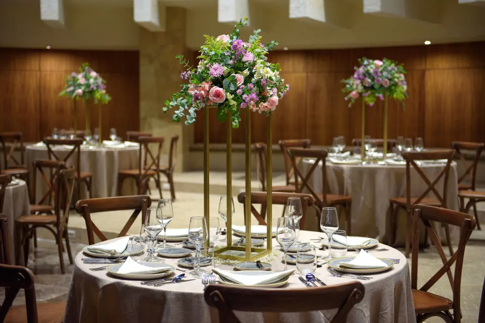 Close-up of a round table with tall floral centerpiece in an event room at Melia Cozumel