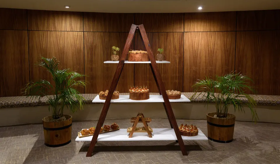 Wooden A-frame display of pastries in a dimly lit event space at Melia Cozumel
