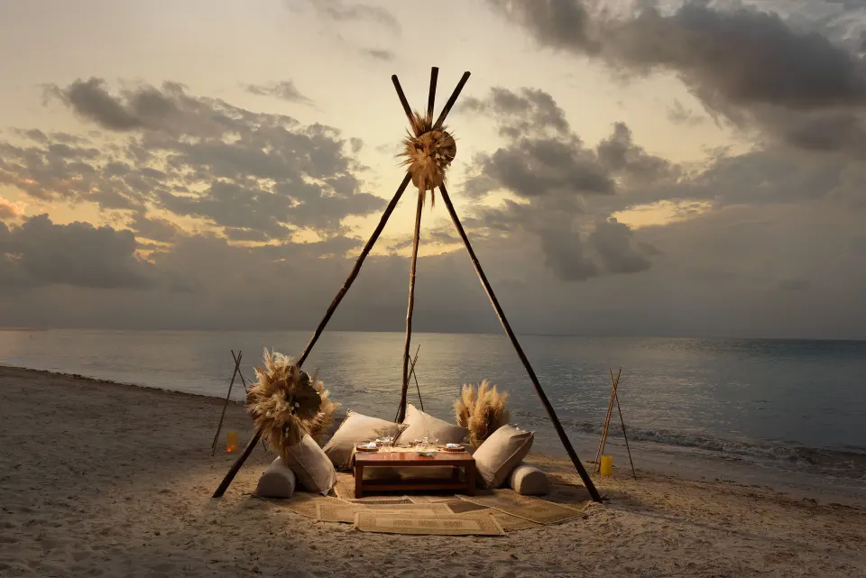 Low teepee-style beach lounge with cushions on Melia Cozumel sand at sunset