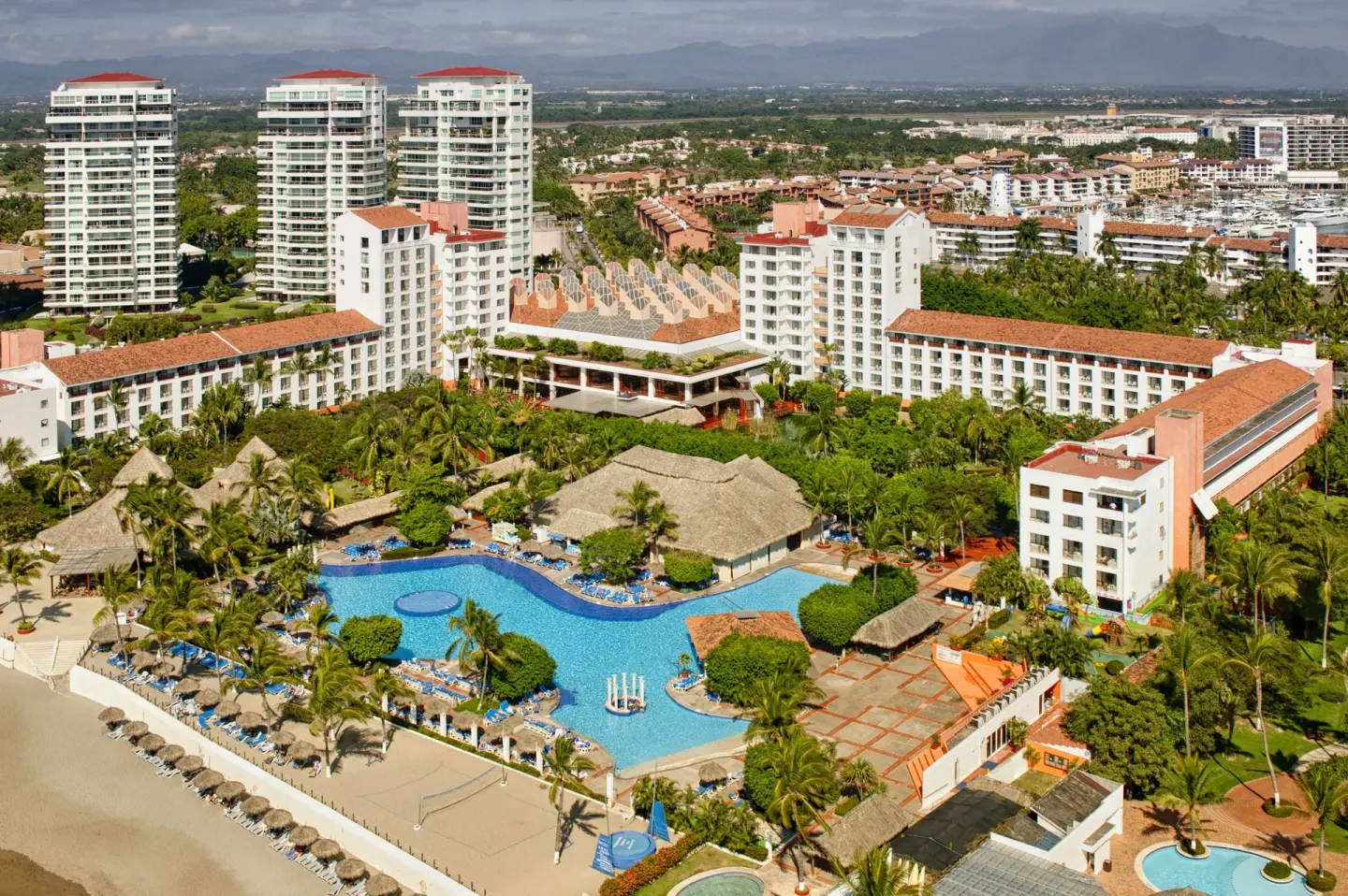 Aerial view of the resort buildings, pool, beach, and palms at Melia Puerto Vallarta.