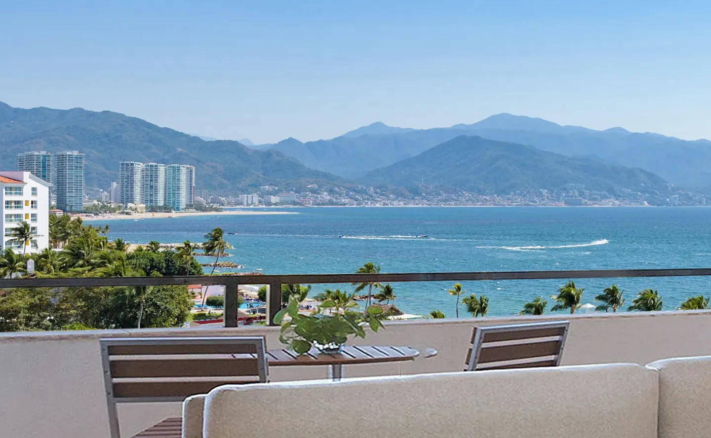 Balcony seating with a bay, coastline, city towers, and mountain view at Melia Puerto Vallarta.