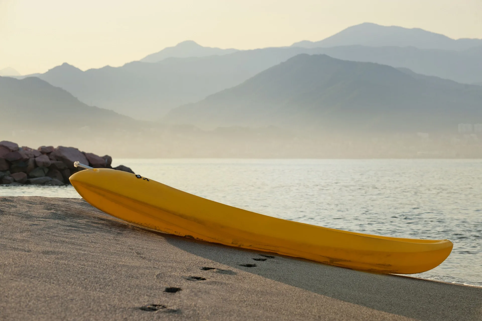 Yellow kayak rests on the beach by the bay at Melia Puerto Vallarta.