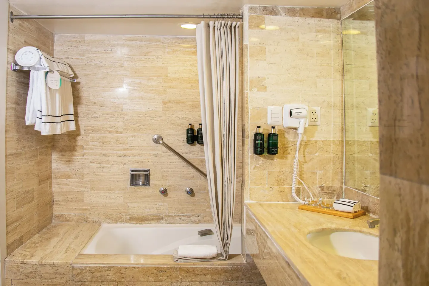 Guest bathroom with bathtub, robe, vanity, and hair dryer at Melia Puerto Vallarta.