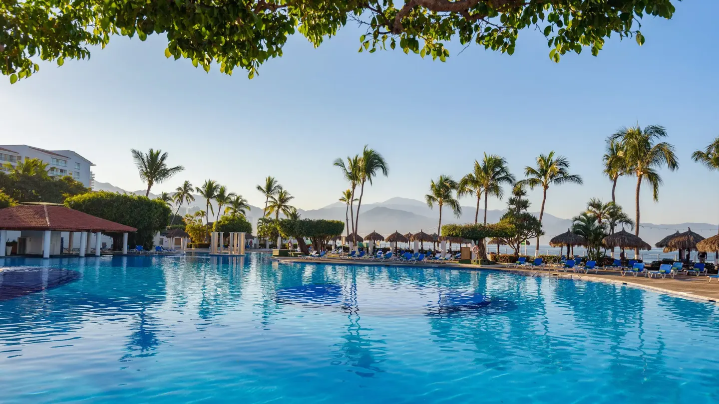 Large resort pool with palms and ocean backdrop at Melia Puerto Vallarta.
