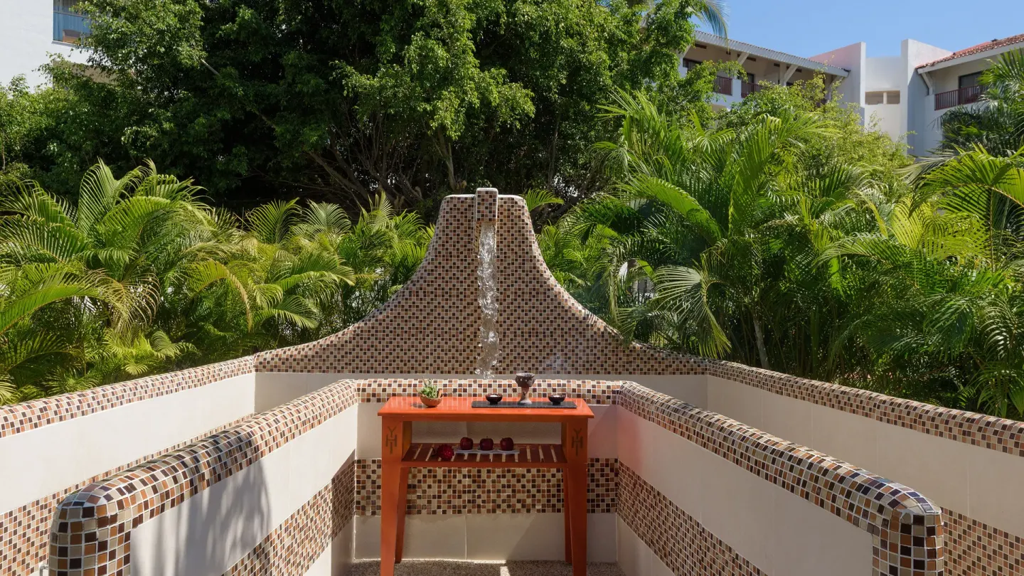Tiled outdoor spa treatment area with fountain and greenery at Melia Puerto Vallarta.