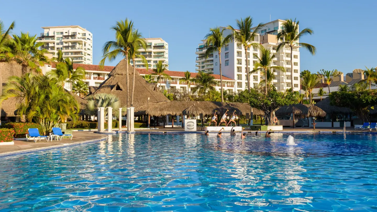 Wide pool view with water exercise class and resort buildings at Melia Puerto Vallarta.