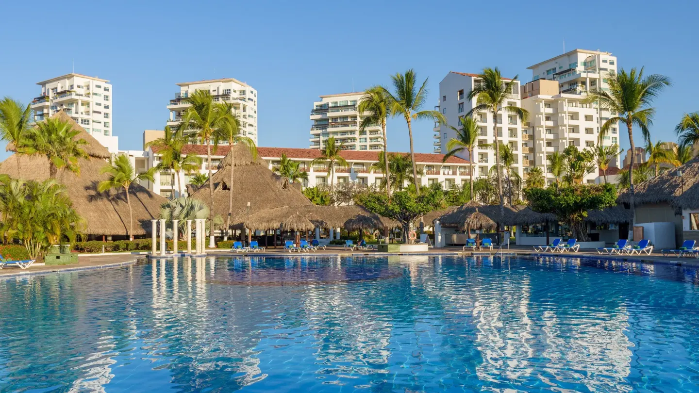 Resort pool with palapas, palms, loungers, and hotel buildings at Melia Puerto Vallarta.