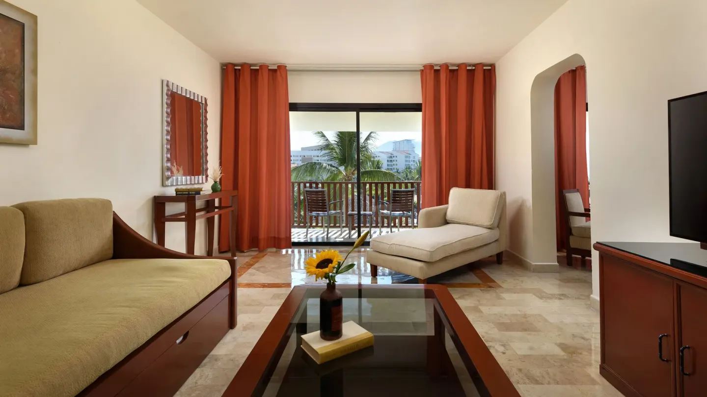 Suite sitting area with balcony, daybed, and TV at Melia Puerto Vallarta.