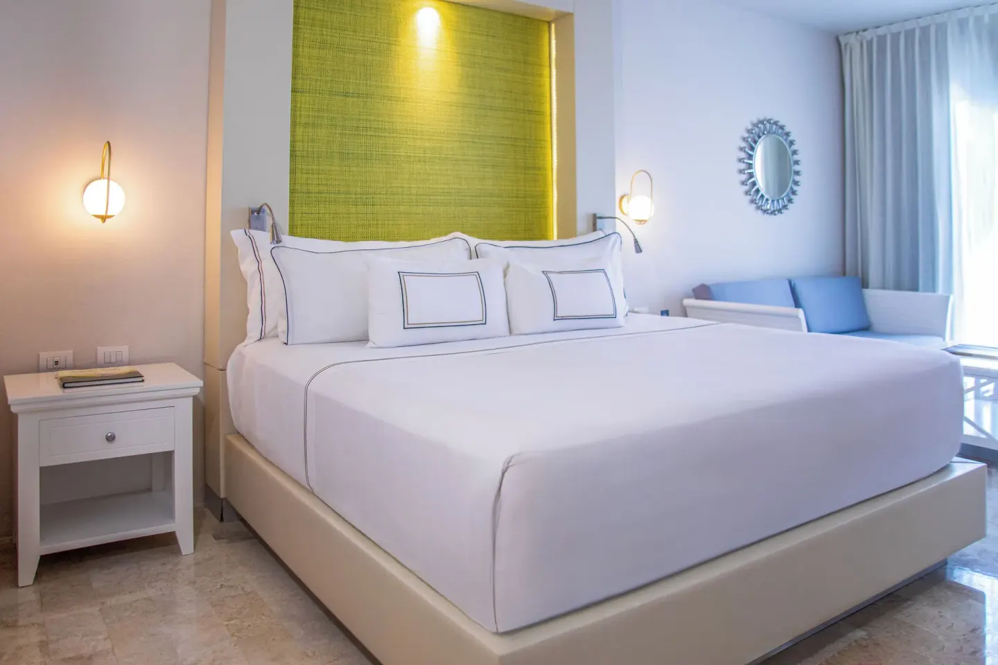 Deluxe Room Sea View king bed with blue sofa and green headboard at Melia Puerto Vallarta.