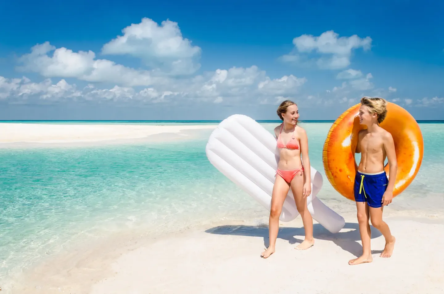 Children carry inflatable floats on a white sand beach at Mia Reef Isla Mujeres.
