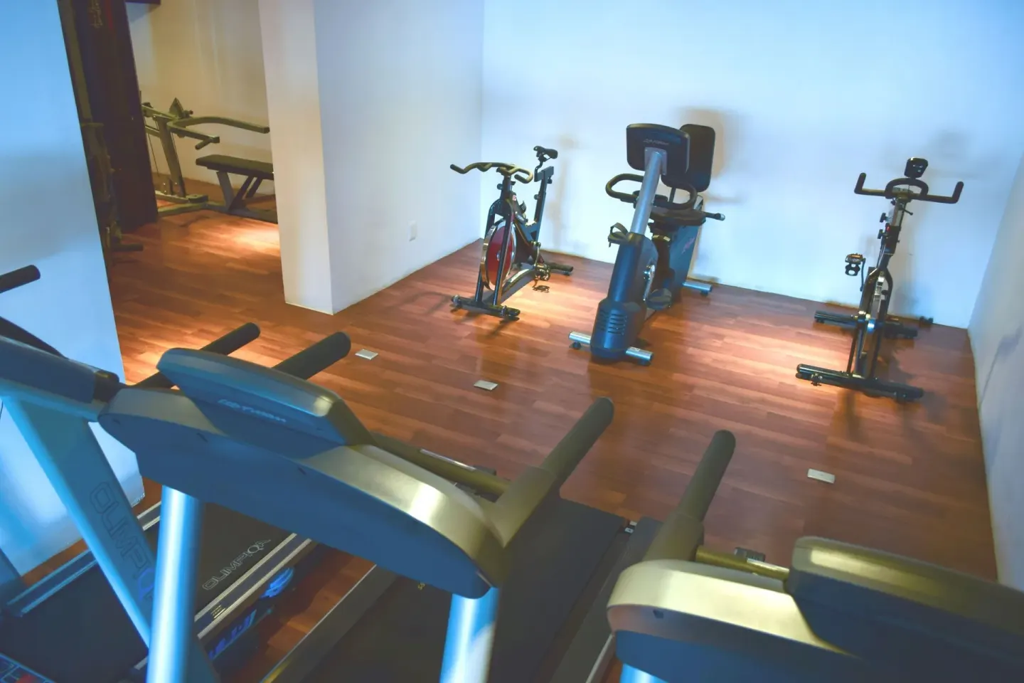 Fitness room with treadmills, stationary bikes, and wood floor at Mia Reef Isla Mujeres.