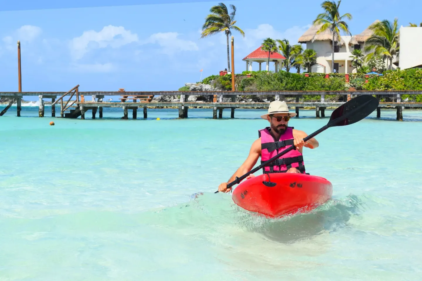 Guest kayaks through shallow turquoise water at Mia Reef Isla Mujeres.