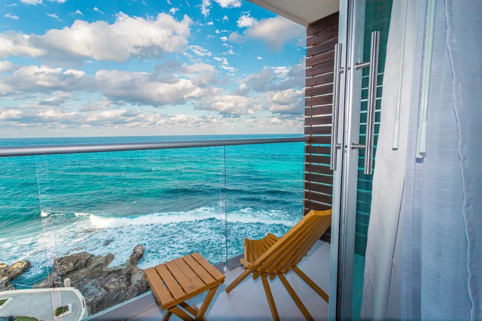 Oceanfront balcony with chair and turquoise sea at Mia Reef Isla Mujeres.
