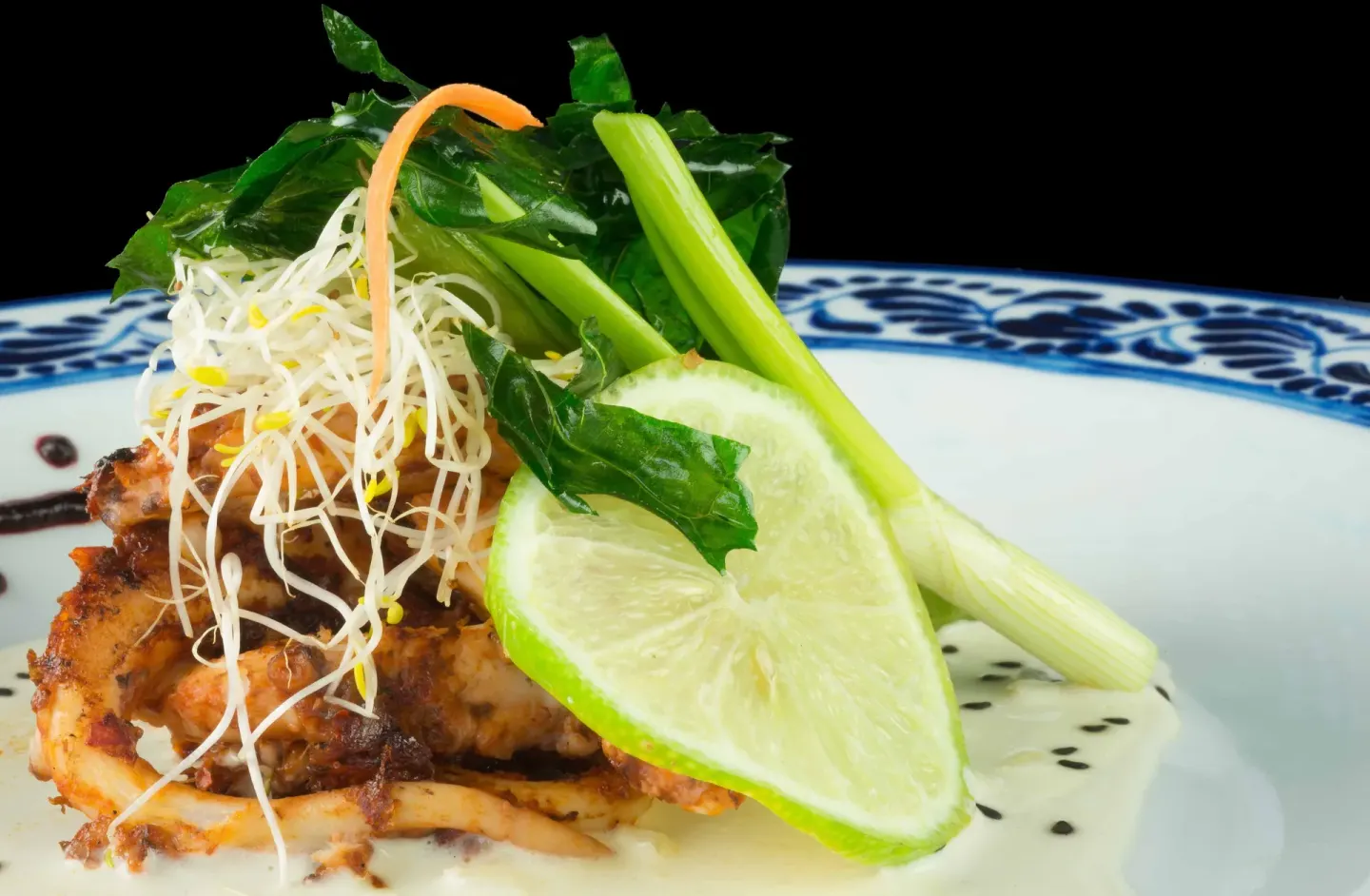 Close-up plated seafood with lime and greens at Mia Reef Isla Mujeres.