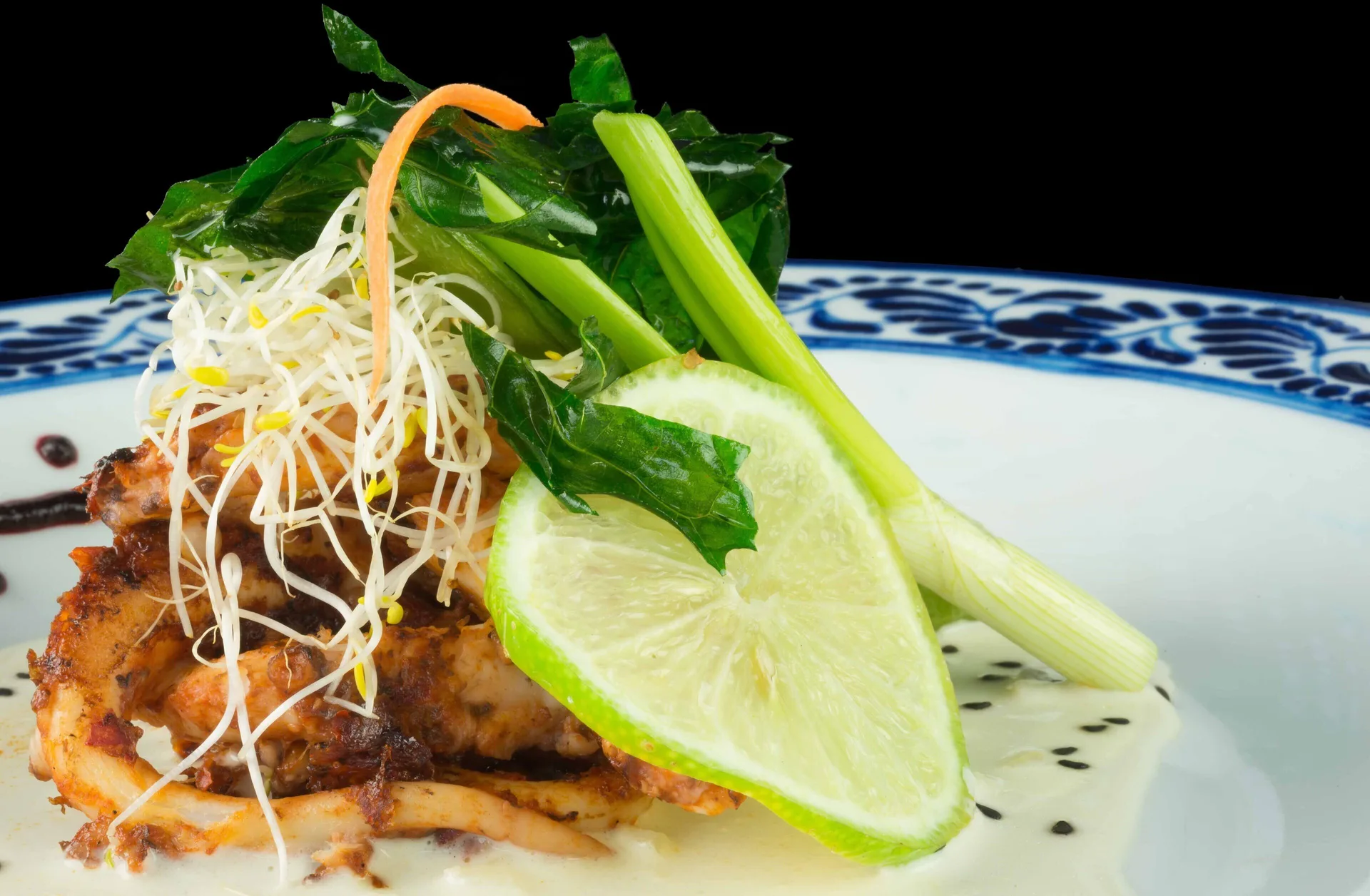 Close-up plated seafood with lime and greens at Mia Reef Isla Mujeres.