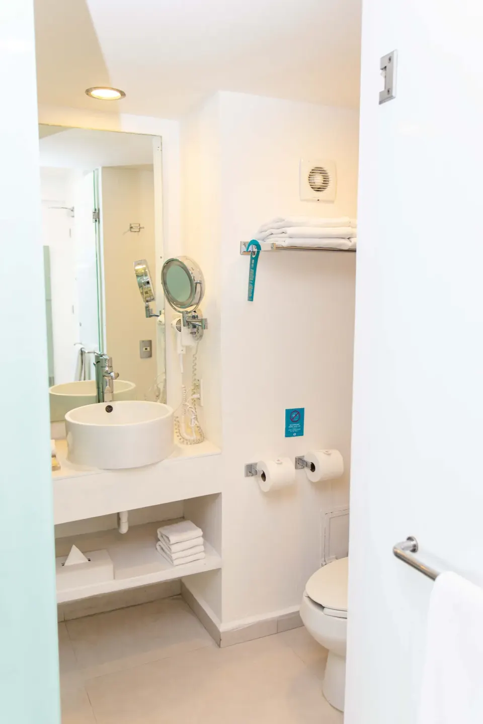 Basic Room bathroom vanity, toilet, towels, and mirror at Mia Reef Isla Mujeres.