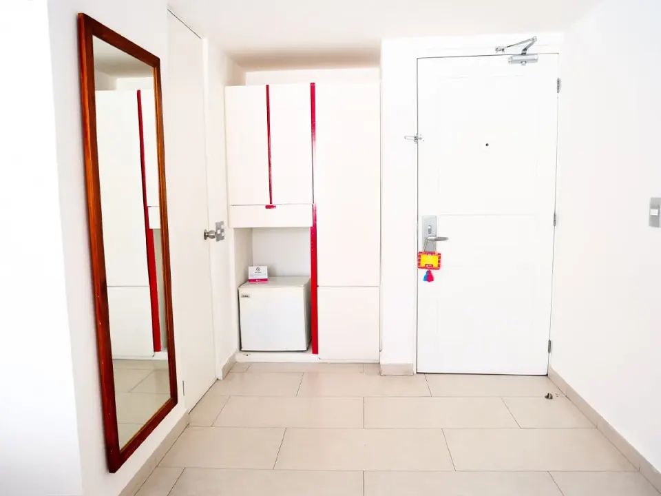 Basic Room entry with mirror, closet, minibar, and white door at Mia Reef Isla Mujeres.